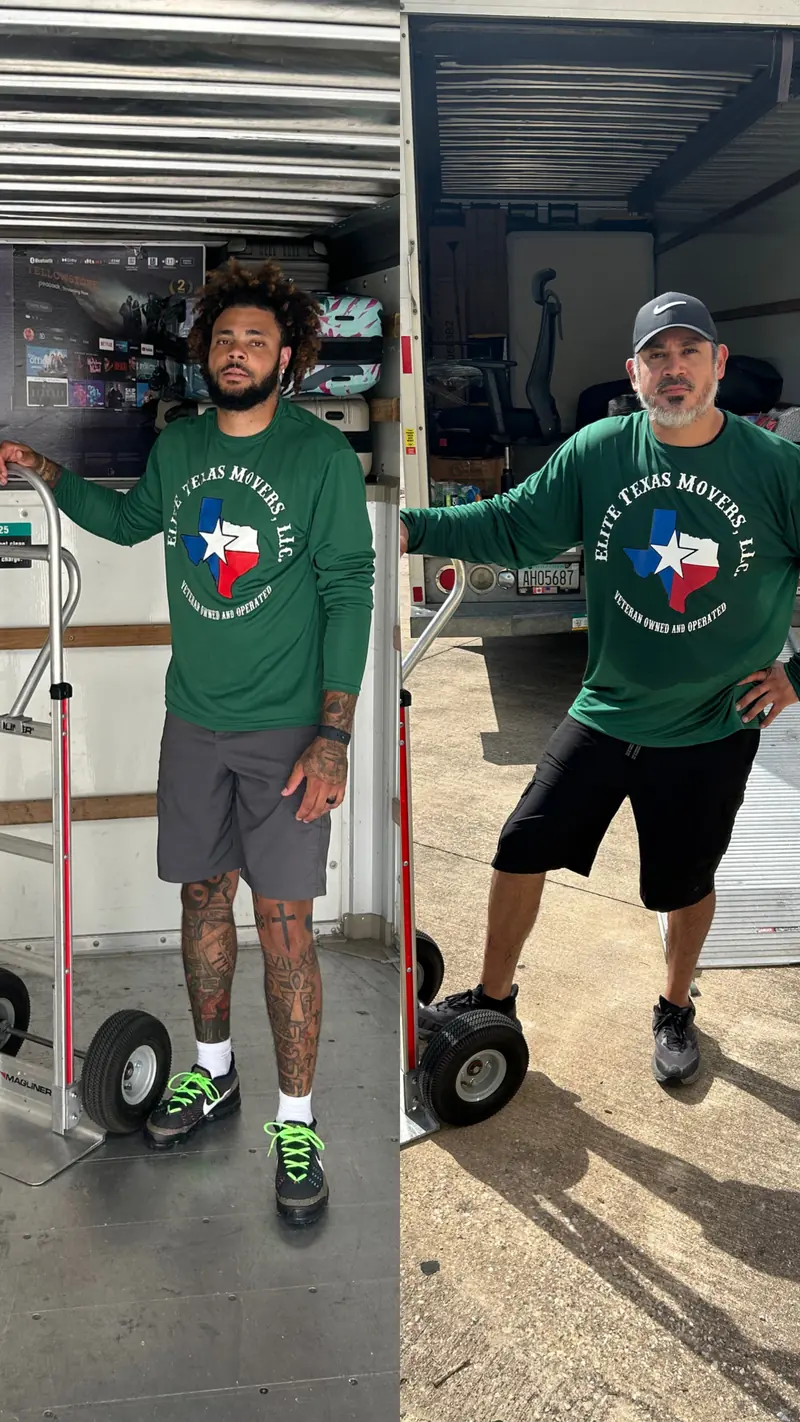 Two of the crew in green Elite Texas Movers shirts beside the truck with hand trucks