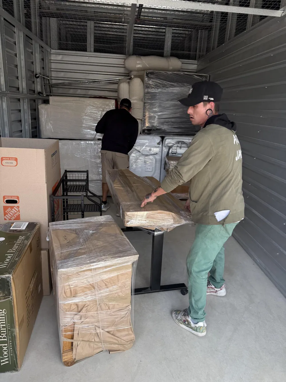 Two of the crew setting wrapped furniture into a storage unit
